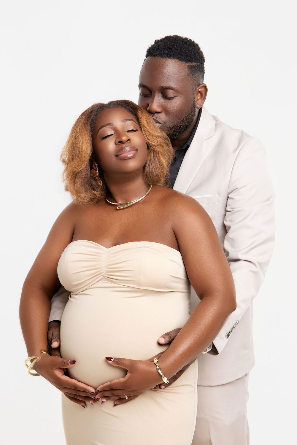 Expecting mother in a peach tulle gown turning toward the light in the studio