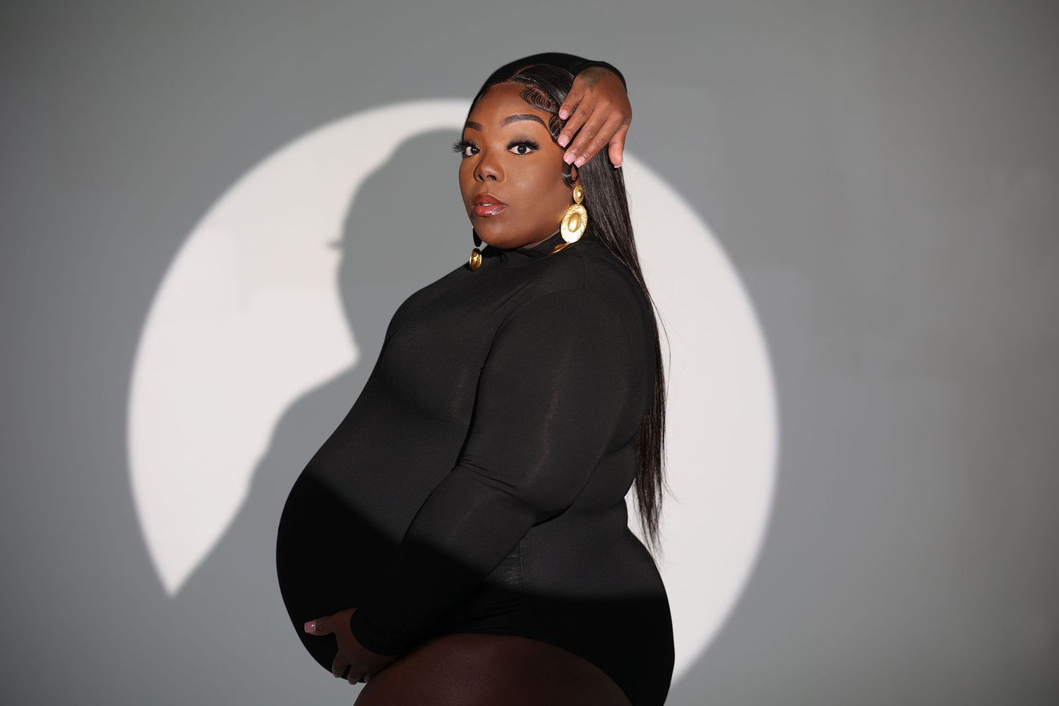 Studio maternity portrait in black against a bright circular backdrop
