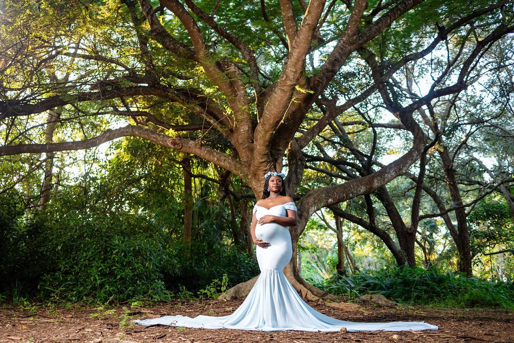 Mother to be in a powder blue gown beneath a spreading oak