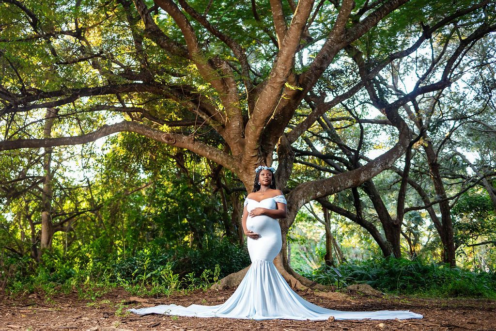 Mother to be in a white gown with a long train under an old oak