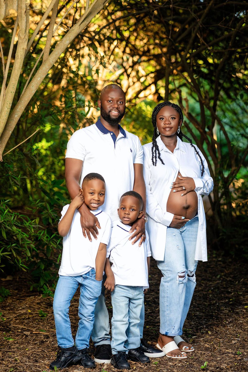 Expecting family in white and denim with their two sons in a garden