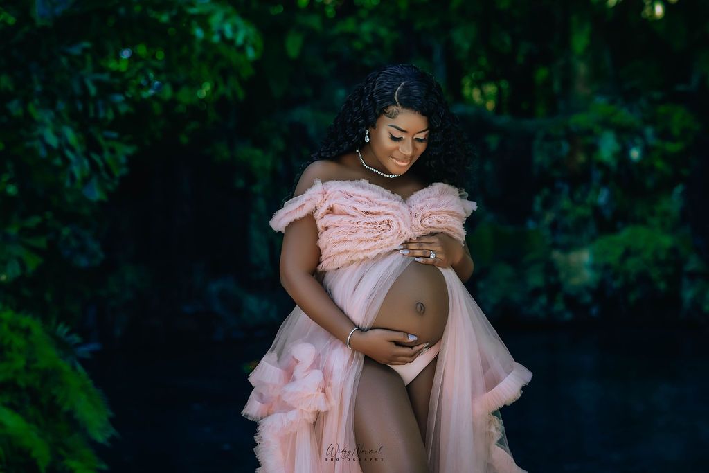 Mother to be in blush tulle beside the dark water of the lagoon
