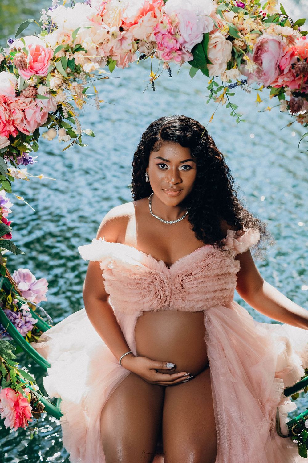 Mother to be in blush tulle against a flower covered wall