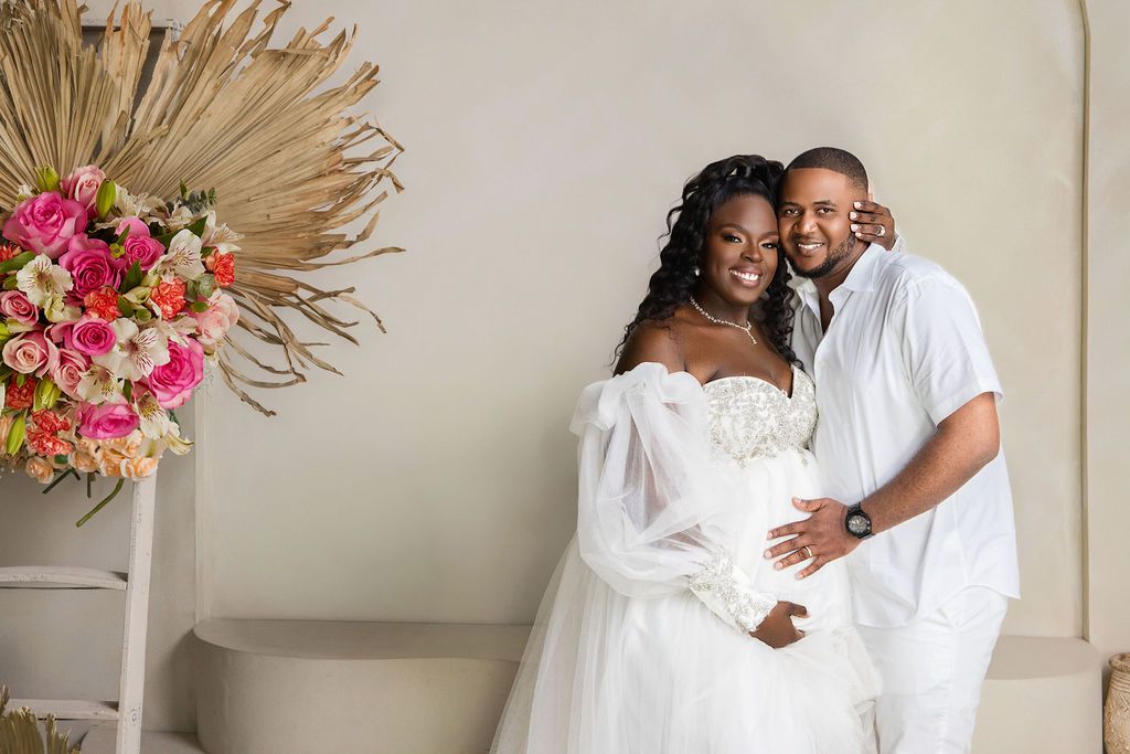 Expecting couple cheek to cheek among coral and pink florals