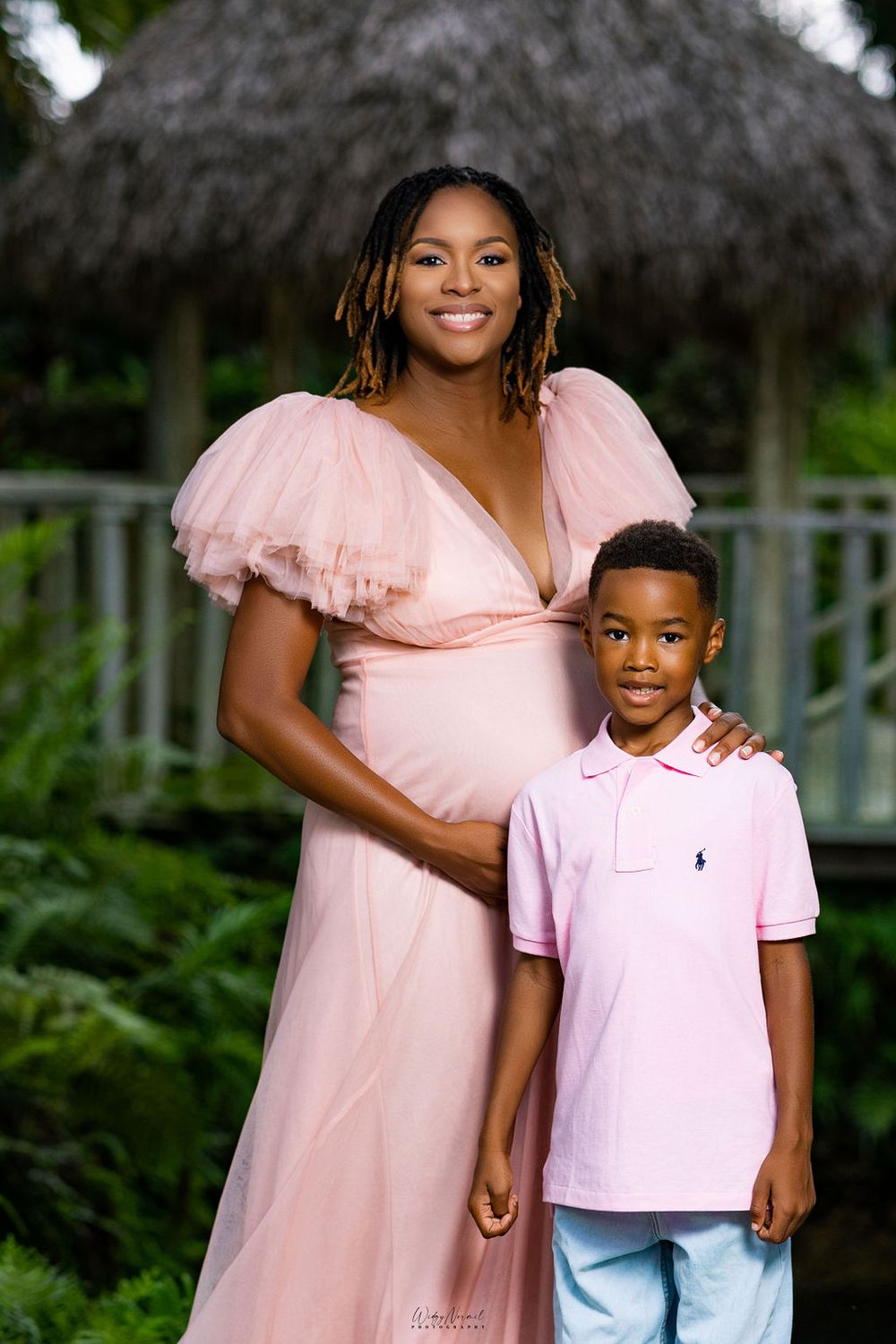 Expectant mother in a blush gown with her young son at her side