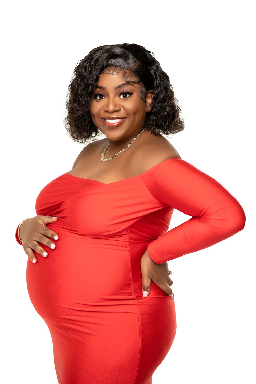 Maternity portrait in a fitted red gown, hands cradling the belly in the studio