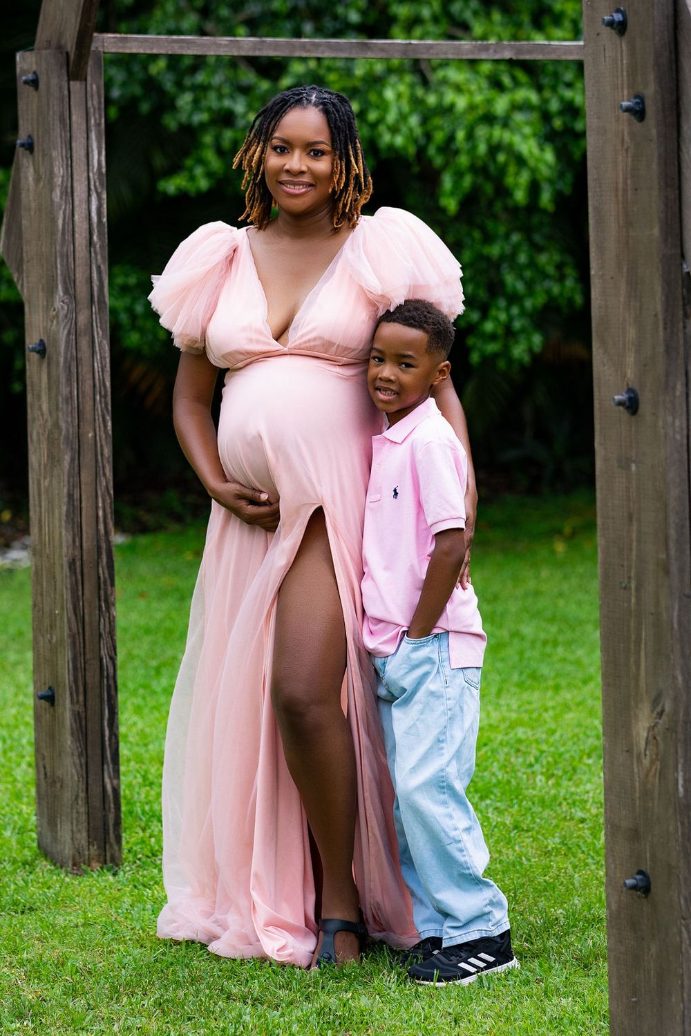 Expectant mother and her son beneath a wooden arbour