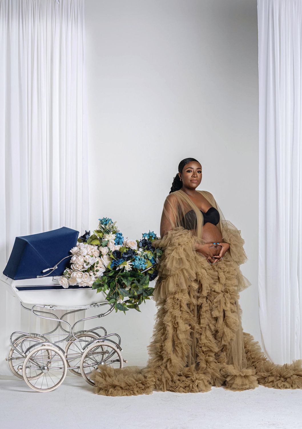 Mother to be in a champagne tulle gown with florals and soft studio light