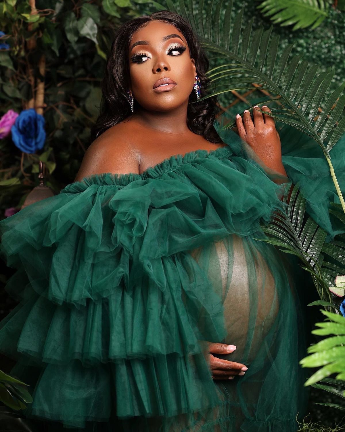 Maternity portrait in green tulle surrounded by tropical foliage