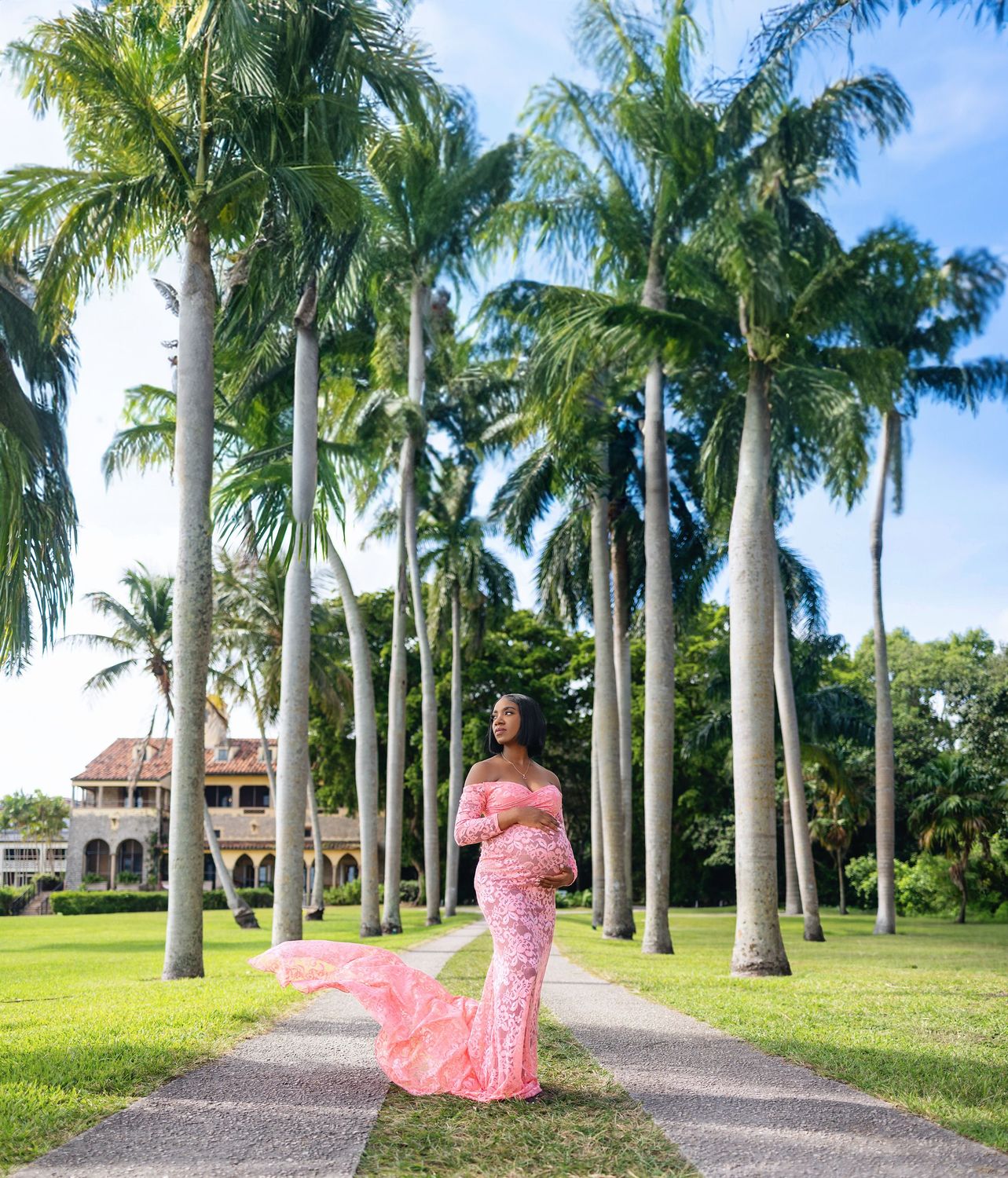 Expecting mother in a pink gown on a royal palm path at Deering Estate