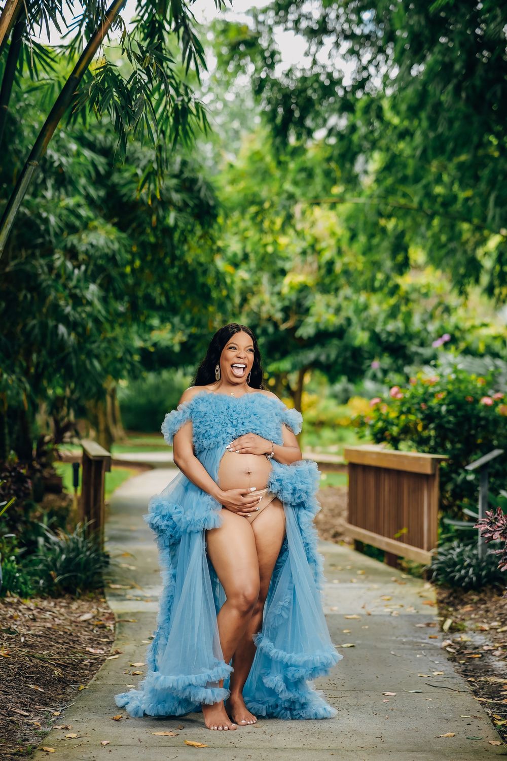 Expectant mother in a blue tulle gown in a tropical garden