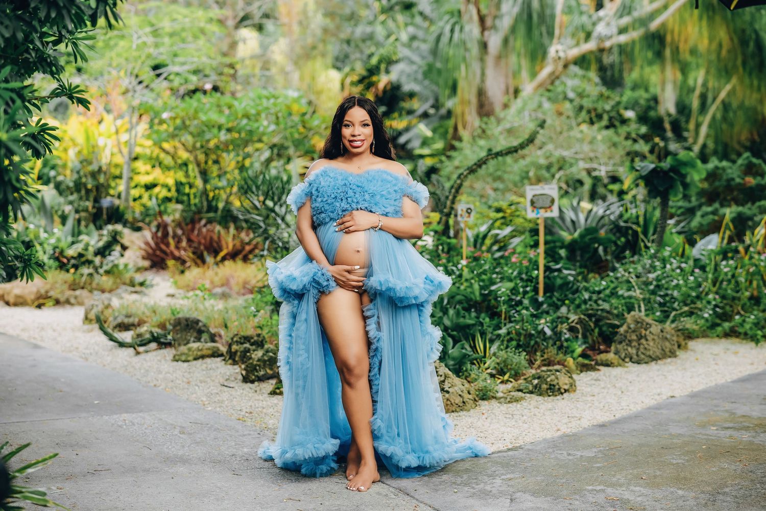 Expecting mother in a blue tulle gown on a garden path in Miami