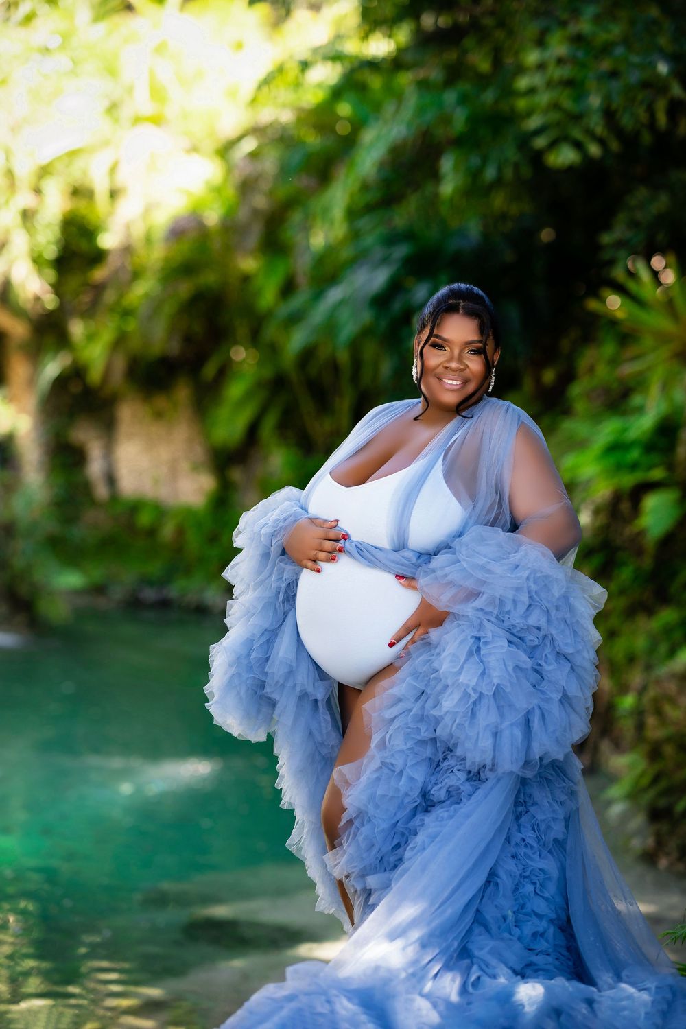 Mother to be in a powder blue ruffled gown at a spring fed lagoon
