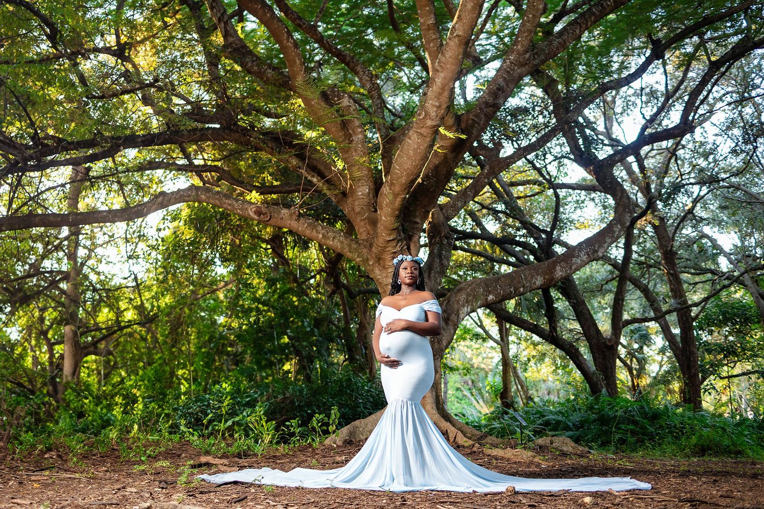 Expectant mother in a blue gown under a canopy of live oaks