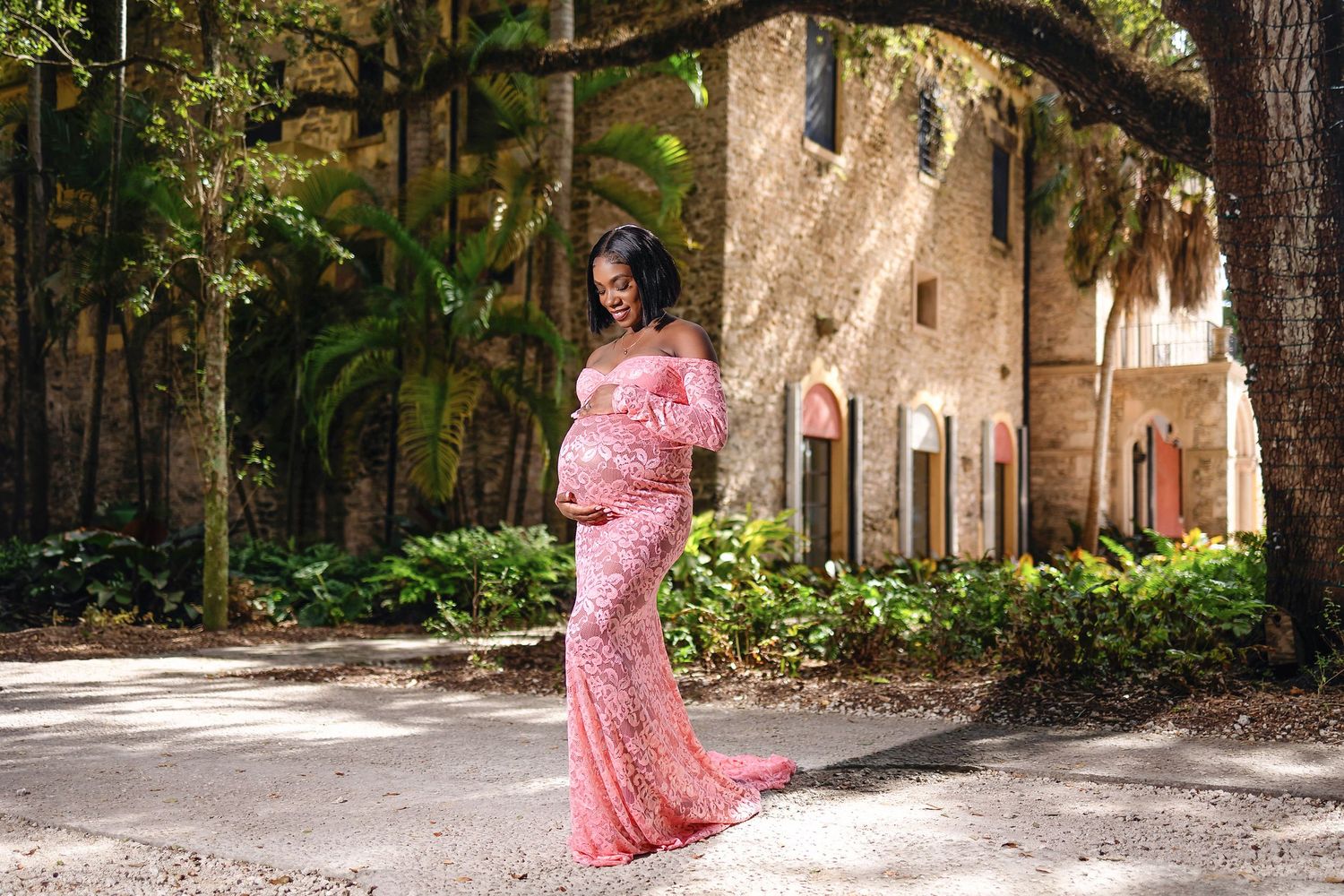 Expecting mother in a blush gown beside the historic stonework at Vizcaya