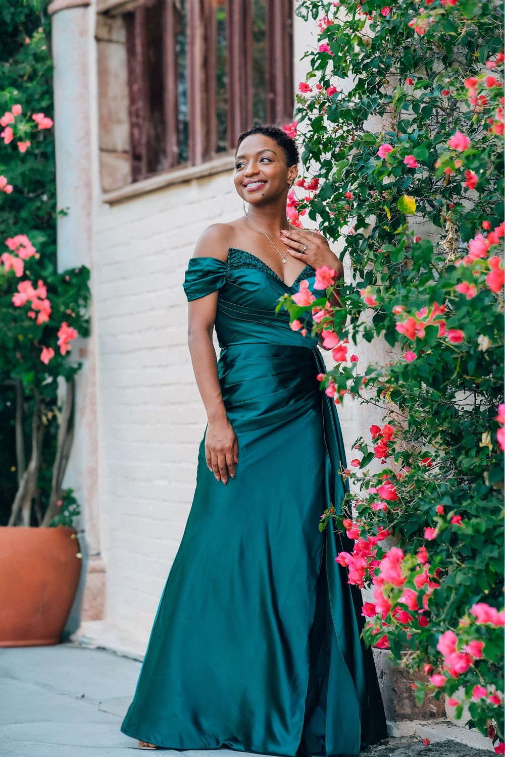 Maternity portrait in a teal gown beside blooming bougainvillea