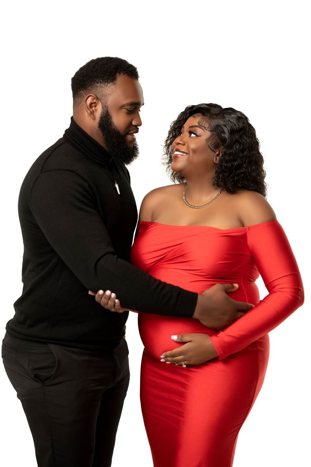 Couple in red and black, partner's hands around her belly, studio portrait