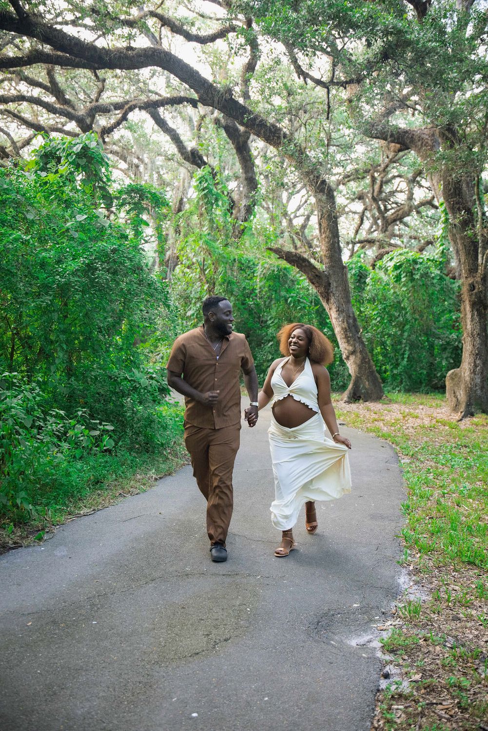 Couple walking a garden path, expectant mother in a cream gown