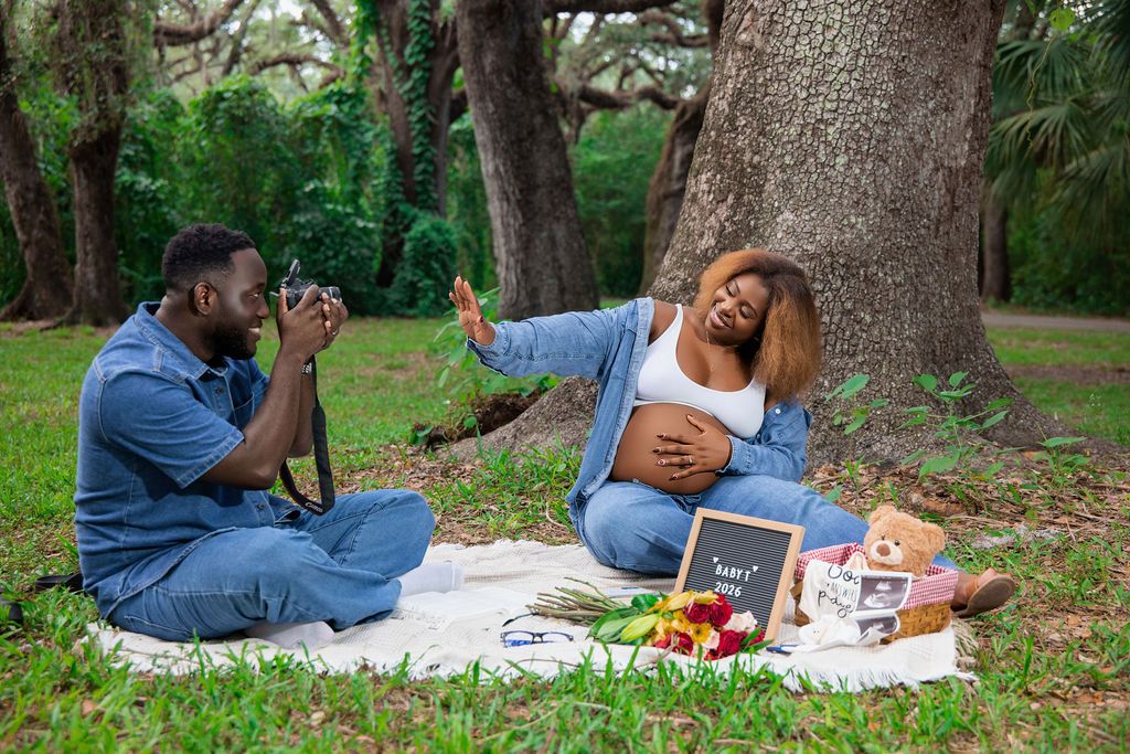 Expecting couple at a picnic set up beneath live oak trees
