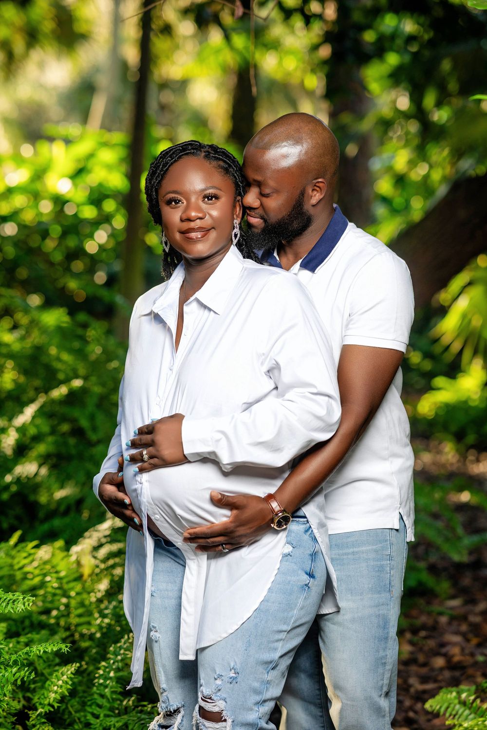 Expecting couple in white in a fern filled garden