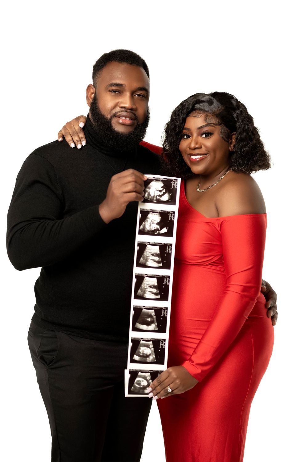 Couple holding an ultrasound strip beside the expectant mother