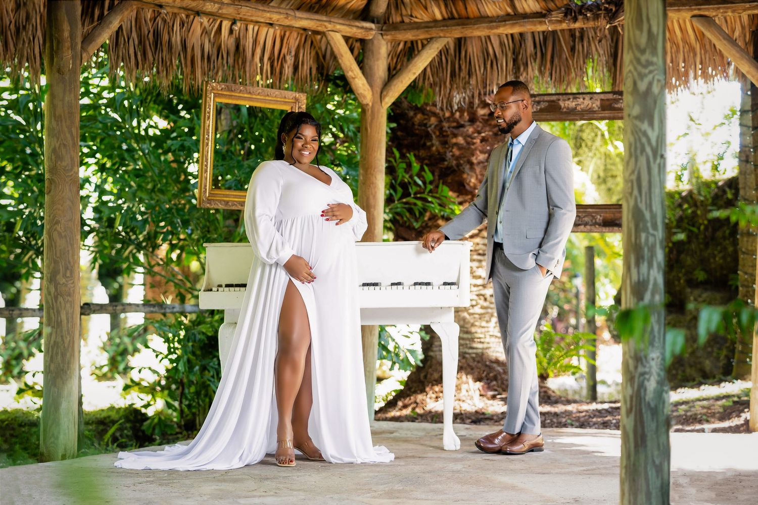 Expecting couple in white beneath a garden gazebo in South Florida