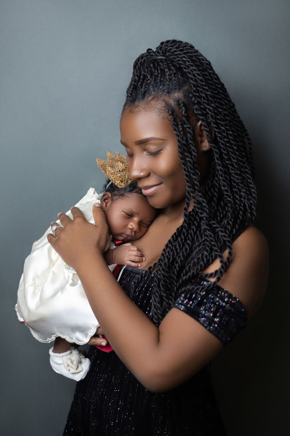New mother holding her sleeping newborn against her shoulder in soft light