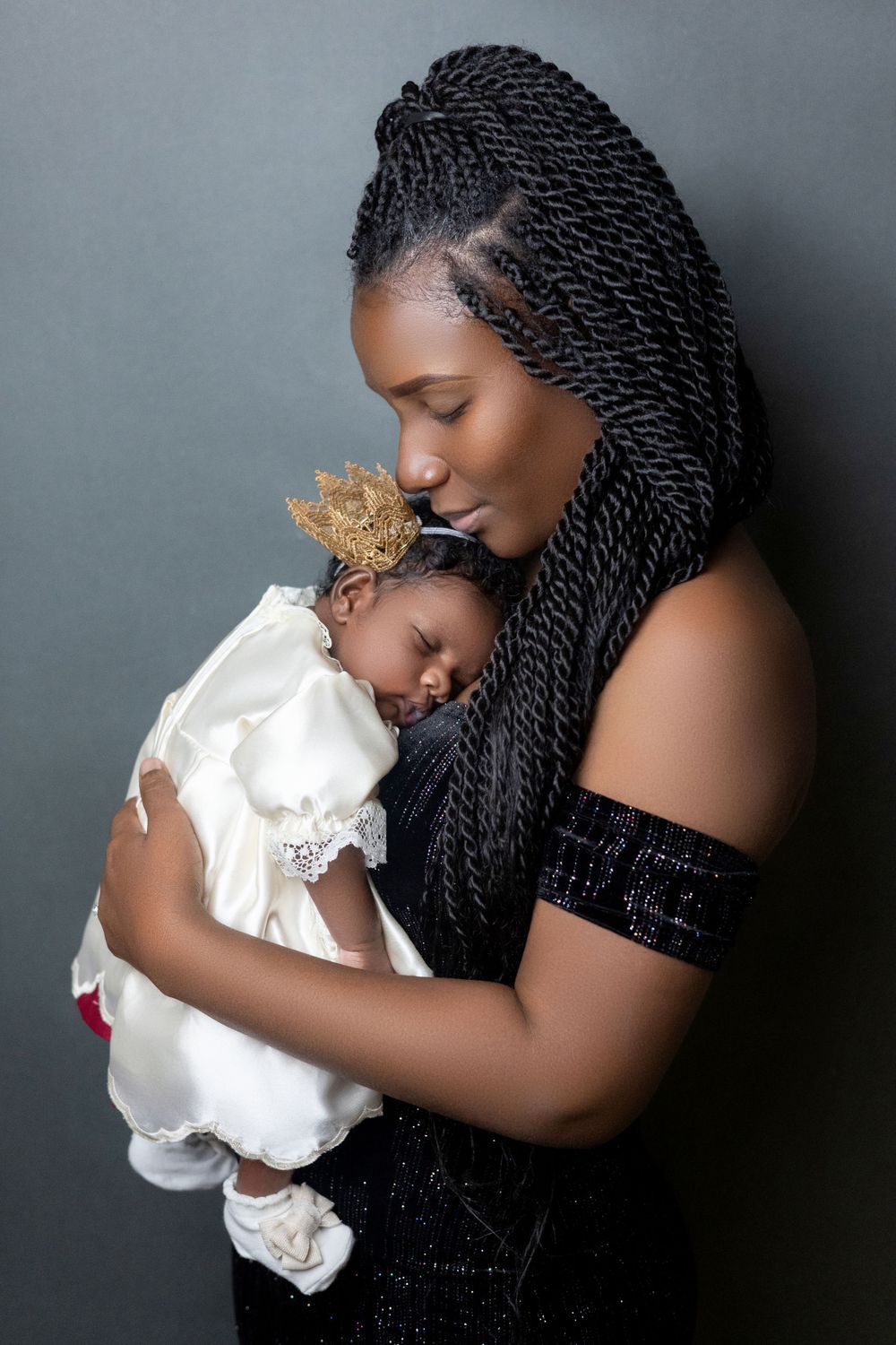 Mother cradling her newborn baby in a christening gown