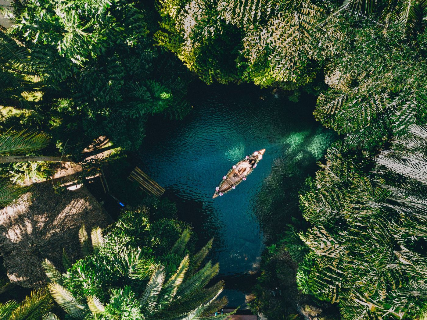 Aerial view of a canoe on a hidden blue lagoon in a Miami jungle garden