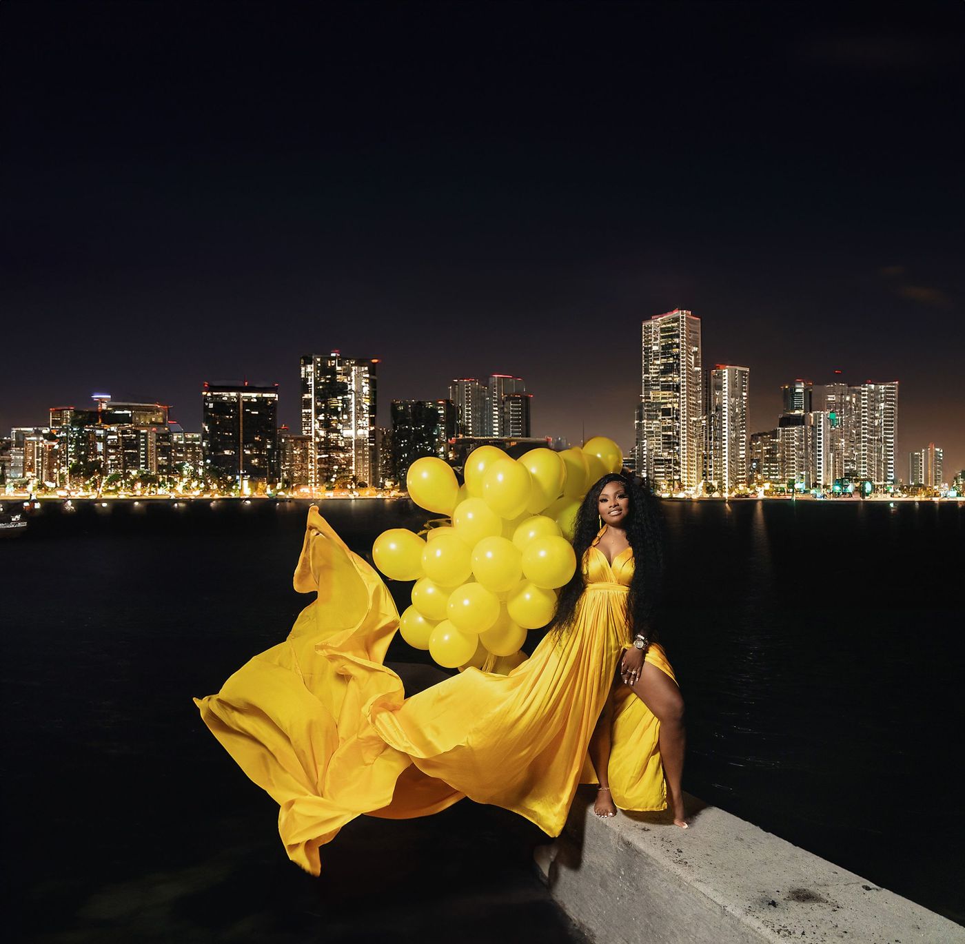 Expectant mother with flowing yellow fabric against the Miami skyline at night
