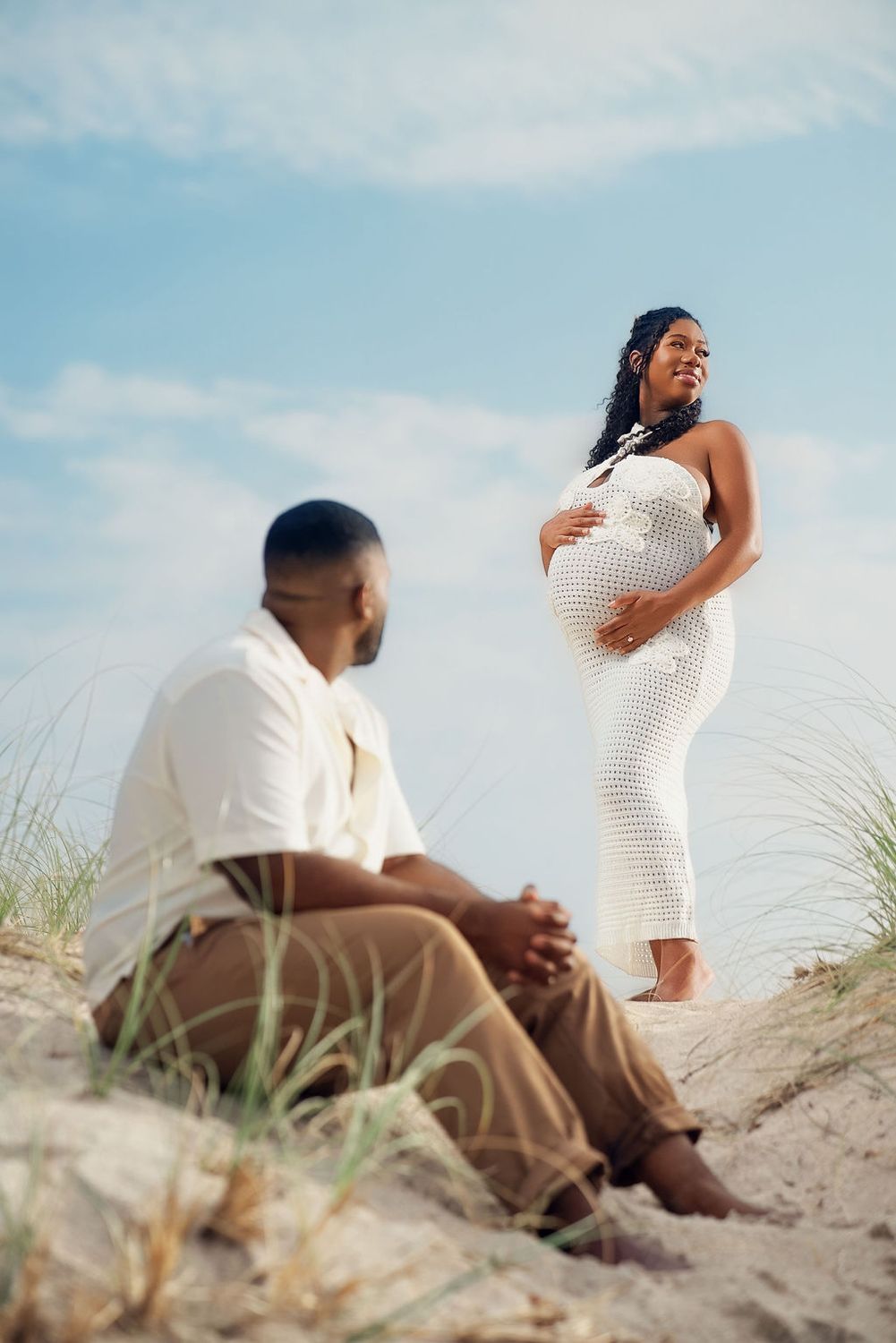 Expectant mother in the beach dunes with her hand on her belly