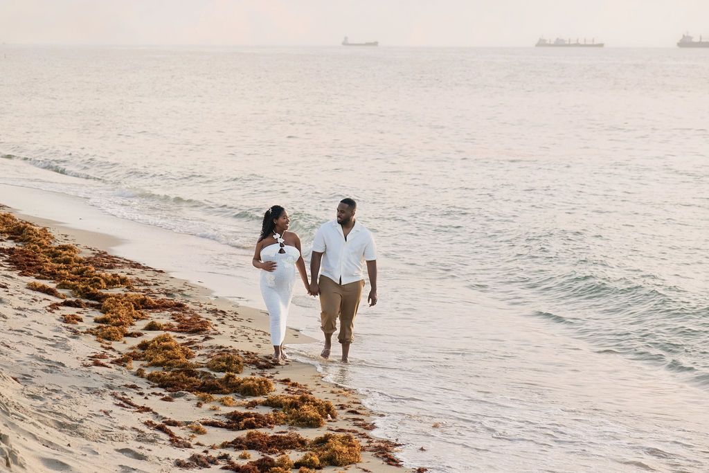 Expecting couple walking the shoreline at first light