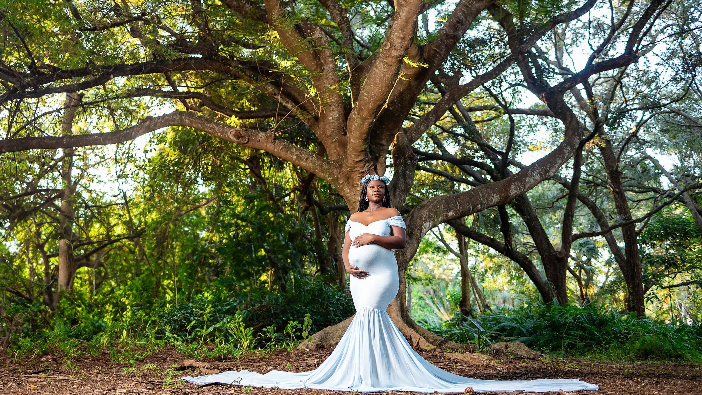 Expectant mother in a white gown beneath a canopy of live oaks in South Florida