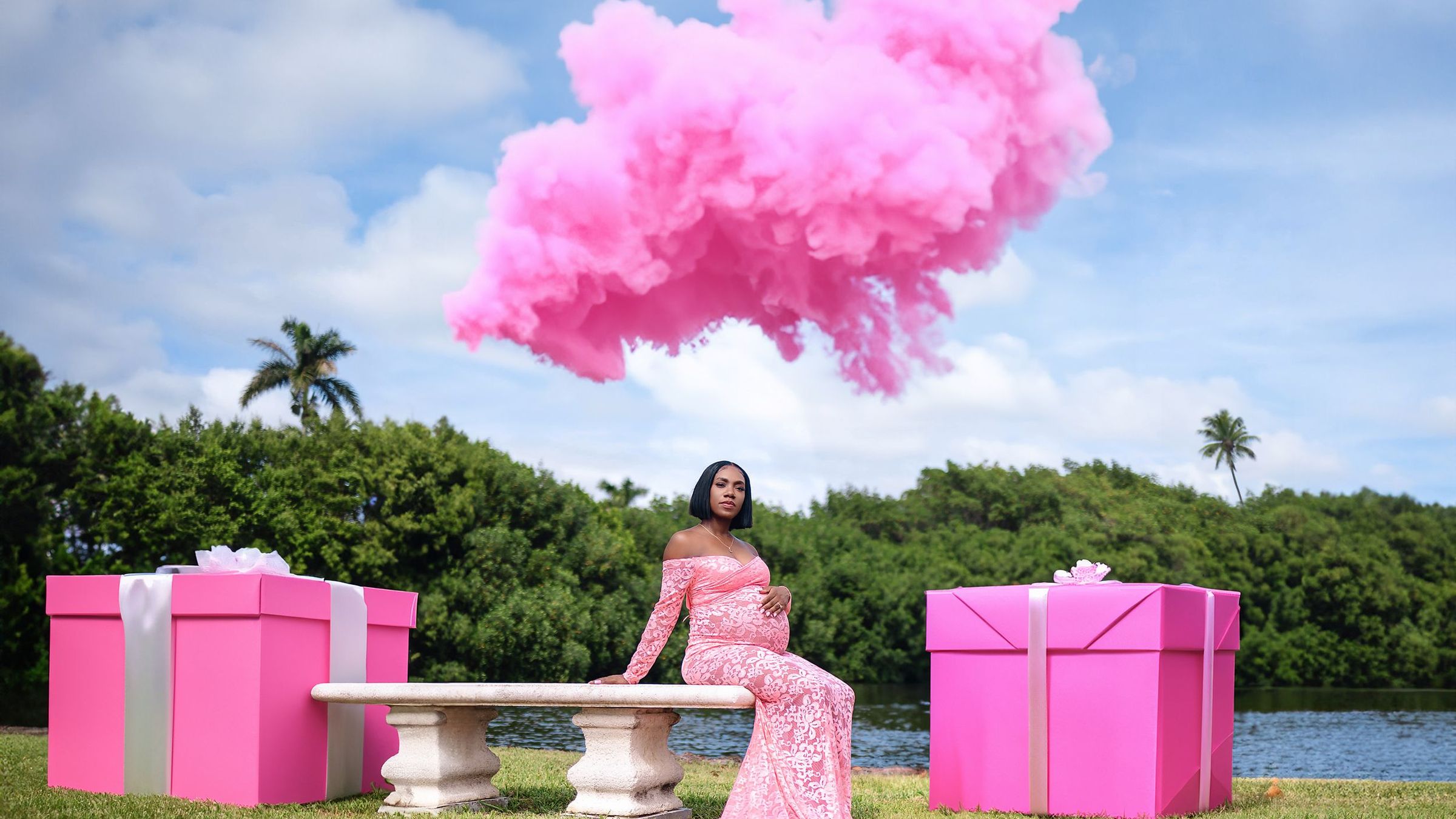 Expectant mother in pink lace beneath a cloud of pink smoke at a gender reveal session